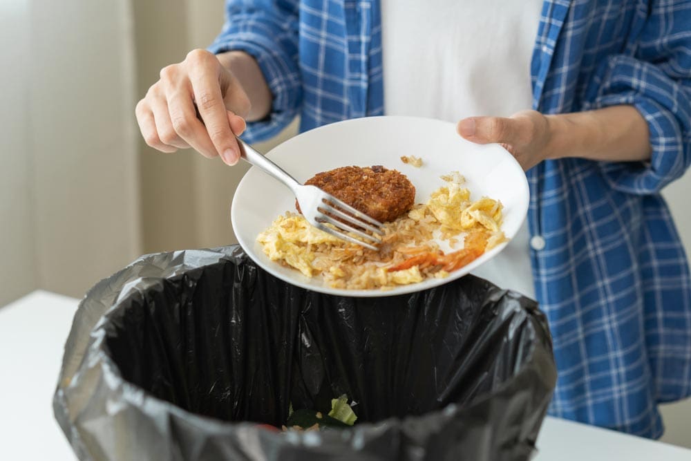 homeowner scraping food waste into the trash bin